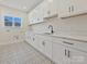 Well-lit laundry room featuring custom cabinets, modern patterned floors, and a large sink at 1160 Springlake Rd, York, SC 29745