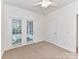 Bright bedroom with carpet flooring, ceiling fan, and access to the backyard through double glass doors at 11705 Silverado Ln, Charlotte, NC 28277