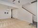 Open-concept living room with carpet, ceiling fan, and staircase access at 12925 Windy Lea Ln, Huntersville, NC 28078