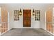 Covered front porch featuring a paneled wood door, decorative sconces, and gray tile flooring at 1441 Carmel Rd, Charlotte, NC 28226