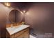 Stylish powder room featuring a round mirror, wood vanity, and elegant gold fixtures at 1441 Carmel Rd, Charlotte, NC 28226