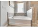 Bright bathroom features a white soaking tub beneath a window, complemented by neutral tile and modern fixtures at 19010 Hawk Haven Ln, Charlotte, NC 28278