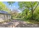 Backyard with storage shed and gravel parking area, grass, and trees at 2125 Kenilworth Ave, Charlotte, NC 28203