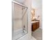Inviting bathroom features a tub/shower with glass doors, a white sink with wooden cabinets, and patterned wallpaper at 2281 Old Salisbury Concord Rd, Concord, NC 28025