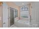 Bright bathroom features a shower, a soaking tub, and a frosted window for privacy at 276 Greyfriars Rd, Mooresville, NC 28117