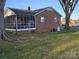 Back of brick home featuring a screened in porch and a well-maintained lawn at 3025 School St, Claremont, NC 28610