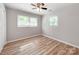 Bright bedroom featuring wood-look flooring, neutral walls, ceiling fan, and natural light from two windows at 4303 Greenhaven Ln, Gastonia, NC 28056