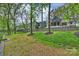 Spacious backyard with retaining wall, mature trees, and views of the house's rear exterior at 438 Wonderwood Dr, Charlotte, NC 28211