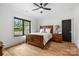 Cozy bedroom featuring a wooden bed, hardwood floors, and a view from a large window at 438 Wonderwood Dr, Charlotte, NC 28211