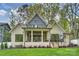 Stunning rear exterior with covered porch, brick facade, well-manicured lawn, and beautiful landscaping at 438 Wonderwood Dr, Charlotte, NC 28211