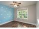 Cozy bedroom featuring wood floors, a ceiling fan and bright blue accent wall at 556 Westwood Dr, Kannapolis, NC 28081