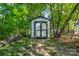 A shed in the backyard surrounded by luscious landscaping and a stack of firewood at 556 Westwood Dr, Kannapolis, NC 28081