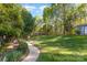 Lush green backyard featuring a stone path, mature landscaping, and a peaceful wooded border at 585 Highland Ridge Rd, Mooresville, NC 28115