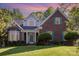 Charming brick home featuring manicured landscaping, a covered porch, and beautiful, colorful sunset at 585 Highland Ridge Rd, Mooresville, NC 28115