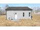 Back exterior view of a single-story home with gray siding, a dark roof, and a small patio area at 606 S 10Th St, Bessemer City, NC 28016