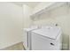 Well-lit laundry room featuring a modern washer and dryer with overhead shelving at 7935 Harrington Woods Rd, Charlotte, NC 28269