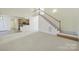 Bright, open-concept area with staircase, carpeted living space, and view of the kitchen at 7935 Harrington Woods Rd, Charlotte, NC 28269