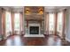 Cozy living room with hardwood floors, a wood-accented fireplace, and large windows at 8810 Cool Meadow Dr, Huntersville, NC 28078
