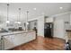 Open concept kitchen with stainless steel refrigerator, wood floors, white cabinets and open access to living room at 9312 Seamill Rd, Charlotte, NC 28278