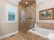 Luxurious bathroom featuring a glass shower, soaking tub, neutral tile, and a framed window with shutters at 9636 Cotton Stand Rd, Charlotte, NC 28277