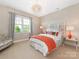 Cozy bedroom featuring a patterned headboard, orange accents, natural light, and plush carpet at 9636 Cotton Stand Rd, Charlotte, NC 28277