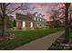 Beautiful brick home with a covered front porch, manicured lawn, and lovely landscaping at sunset at 135 Northbridge Dr, Mooresville, NC 28115