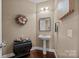 Charming half bathroom with pedestal sink, decorative mirror, and wood floors; convenient for guests at 135 Northbridge Dr, Mooresville, NC 28115