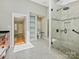 Modern bathroom featuring a glass-enclosed shower, tiled floors, built-in shelves and access to an adjacent room at 1413 Willow Oaks Trl, Weddington, NC 28104