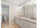 Bright bathroom with double vanity with granite countertops and a view into an adjacent room at 1413 Willow Oaks Trl, Weddington, NC 28104