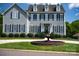 Charming gray two-story home featuring black shutters, a well-manicured lawn, and an inviting circular fountain at 143 S Gibbs Rd, Mooresville, NC 28117