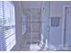 Modern glass shower with white marble tiled walls, shower head, and sunlit window blinds at 143 S Gibbs Rd, Mooresville, NC 28117