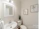 Clean, neutral-toned powder room with a decorative mirror and wall art at 16718 Hampton Crossing Dr, Huntersville, NC 28078