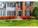 Close-up of a home's front exterior with a beautiful yard and blooming red bushes leading up to a black front door at 16718 Hampton Crossing Dr, Huntersville, NC 28078