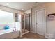 Well-lit bathroom showcasing a soaking tub, glass enclosed shower, and a white door at 17712 Yarwill Ct, Charlotte, NC 28278