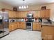 Functional kitchen featuring tile flooring, wood cabinets, and modern stainless steel appliances at 2206 Golden Larch Ln, Waxhaw, NC 28173