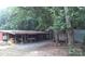 Rustic farm with an outbuilding featuring a work table with hay in a barn, surrounded by lush trees and greenery at 3014 Haigler Rd, Monroe, NC 28110