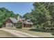 Charming log cabin home with American flag, stone chimney, and inviting front porch at 3014 Haigler Rd, Monroe, NC 28110