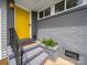 Inviting front porch with a vibrant yellow door, gray brick siding, and sleek black railing at 4024 Seaforth Dr, Charlotte, NC 28205
