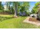 Spacious backyard showcasing a custom blue shed, lush lawn, and mature trees at 4626 Fairbluff Pl, Charlotte, NC 28209