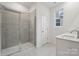 A bathroom with tiled floor and shower, a clear shower screen, and a white sink and cabinet at 562 Mountain View Dr, Monroe, NC 28110