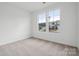 A bedroom with carpeted floors and plain white walls with two windows showing neighboring homes at 562 Mountain View Dr, Monroe, NC 28110