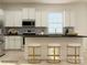 Bright kitchen with white cabinets, island with seating, and stainless steel appliances at 8442 Norman Forest Rd, Lancaster, SC 29720