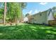 A spacious backyard offers lush lawn, mature trees, and an outdoor seating area with a fire pit at 8707 Copenhagen Ln, Charlotte, NC 28216