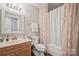 Bathroom with a wooden vanity, framed mirror, decorative light fixture, and shower-tub combination at 8707 Copenhagen Ln, Charlotte, NC 28216