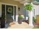 Inviting front porch featuring a decorated door, a fern, potted plants, and stylish decor at 8707 Copenhagen Ln, Charlotte, NC 28216