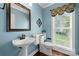 Powder room with blue walls, pedestal sink, and decorative mirror at 8929 Lizzie Ln, Huntersville, NC 28078