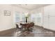 Dining room with a modern chandelier, wood table, chairs, large windows, and sleek flooring at 908 Cypress Point Ln # 218, Monroe, NC 28112