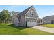 Side view of a home featuring a two-car garage, green lawn, and attractive landscaping at 908 Cypress Point Ln # 218, Monroe, NC 28112