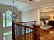 Elegant hallway with wrought iron railing, wood floors, and a view into the primary bedroom with a chandelier at 9508 Hayenridge Ct, Huntersville, NC 28078