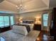 Spacious main bedroom features a tray ceiling, chandelier, hardwood floors, and large windows with plenty of natural light at 9508 Hayenridge Ct, Huntersville, NC 28078